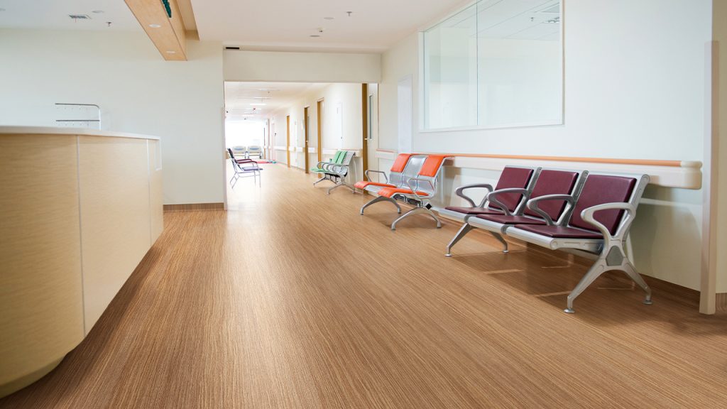 Polyflor Expona Flow luxury vinyl tiles in a hospital waiting area, showing warm wood-effect design with safety performance
